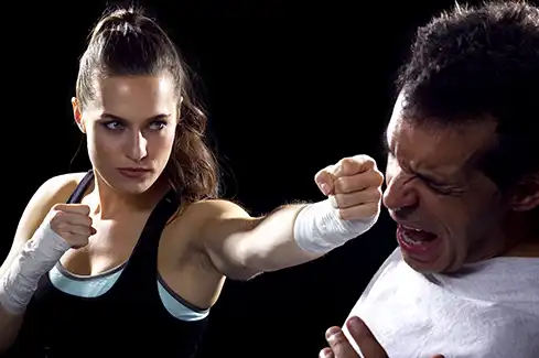 Woman delivers a powerful punch during a Krav Maga self-defense training exercise, demonstrating practical striking techniques for personal protection at Krav Maga Chapel Hill.